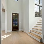 Bright and spacious home entryway featuring wooden flooring and large windows.
