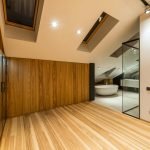 Creative design of bathroom with bath on floor under windows illuminated by lamps in house